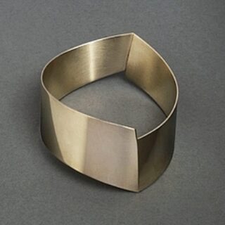 Offener, breiter Armreif aus gebürstetem Metall mit eckiger, asymmetrischer Form
