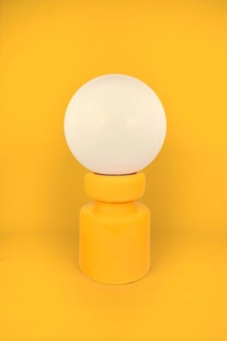 Floor lamp with spherical lampshade on cylindrical base, against yellow background.