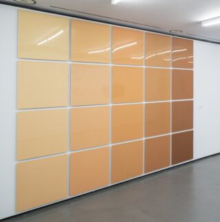 Large wall artwork composed of square panels in various shades of yellow and brown.