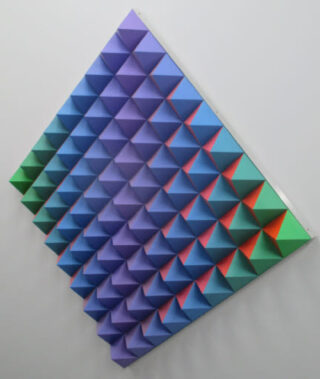 Three-dimensional wall piece with pyramid-shaped elements in a gradient from green through blue to red.