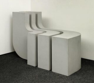 Three nested minimalist benches with rounded backrests placed in a room corner.