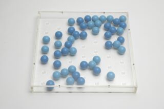 Square, transparent Plexiglas object containing several blue wooden spheres.