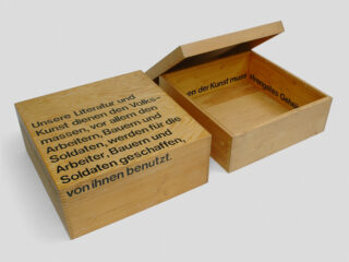 Open wooden box with black text on the lid and base.