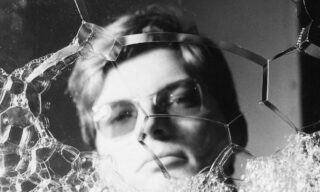 Young man with glasses behind soap bubbles.
