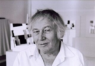 Portrait of an older man with slightly tousled hair in his studio.
