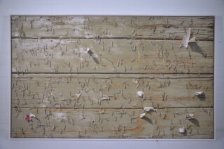 Canvas on a stretcher frame with a weathered, wood-like surface, metal staples, and paper fragments.
